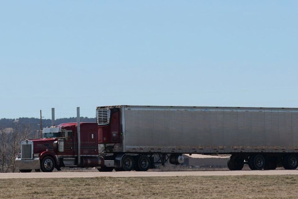 Long-nose tractor pulling a trailer along a two-lane highway