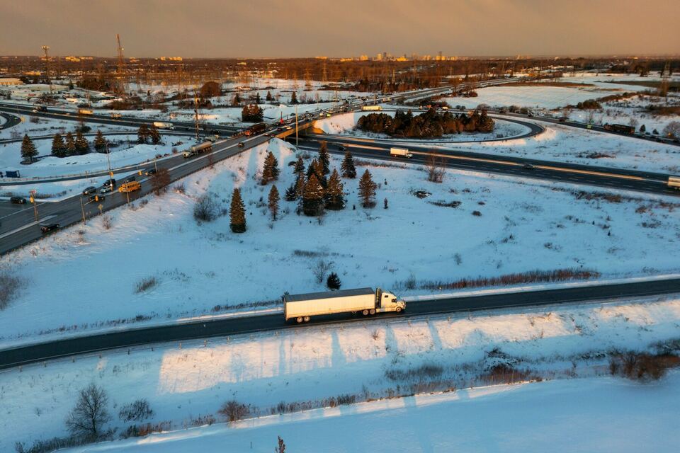 Aerial view of a tractor-trailer on a snowy highway at sunset