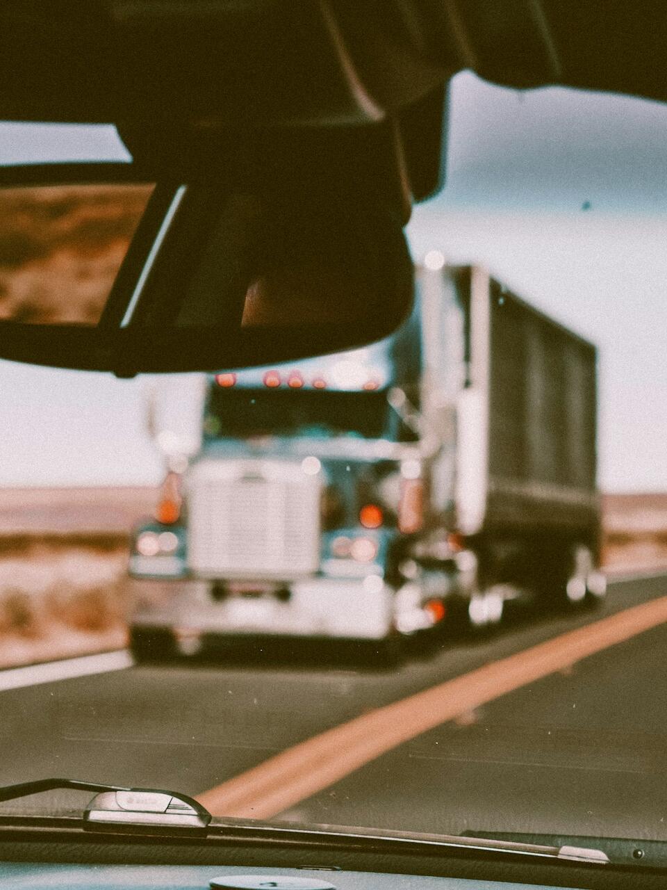 View through a truck windshield of an oncoming semi on the highway